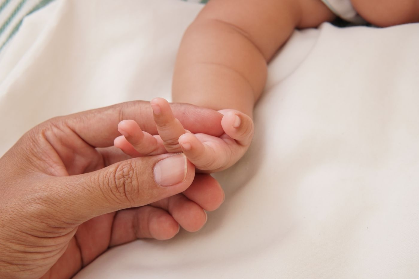 Main d'un bebe autour d'un doigt
