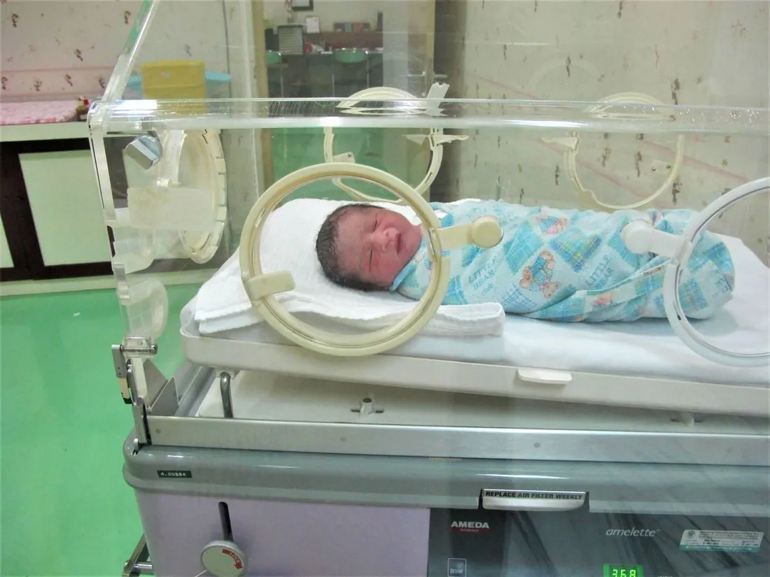 Soignante aupres d'un bebe en couveuse, service de neonatologie